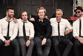 Soulband in zwart-wit, zittend in stijl met witte overhemden en zwarte stropdassen – een stijlvolle en tijdloze bandfoto.